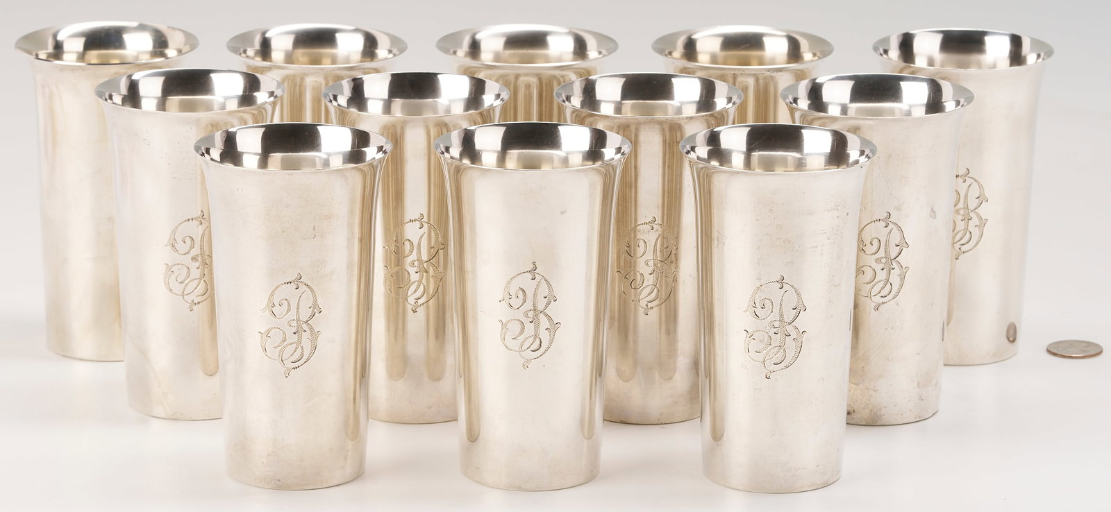 12 Sterling Silver Highball Glasses: Assembled set of twelve (12) Wallace Sterling Silver Highball Glasses. Each of tall tapering form with flaring rim. Eight are marked for M. Fred Hirsch Co. #97 with script monogram B, the remaining