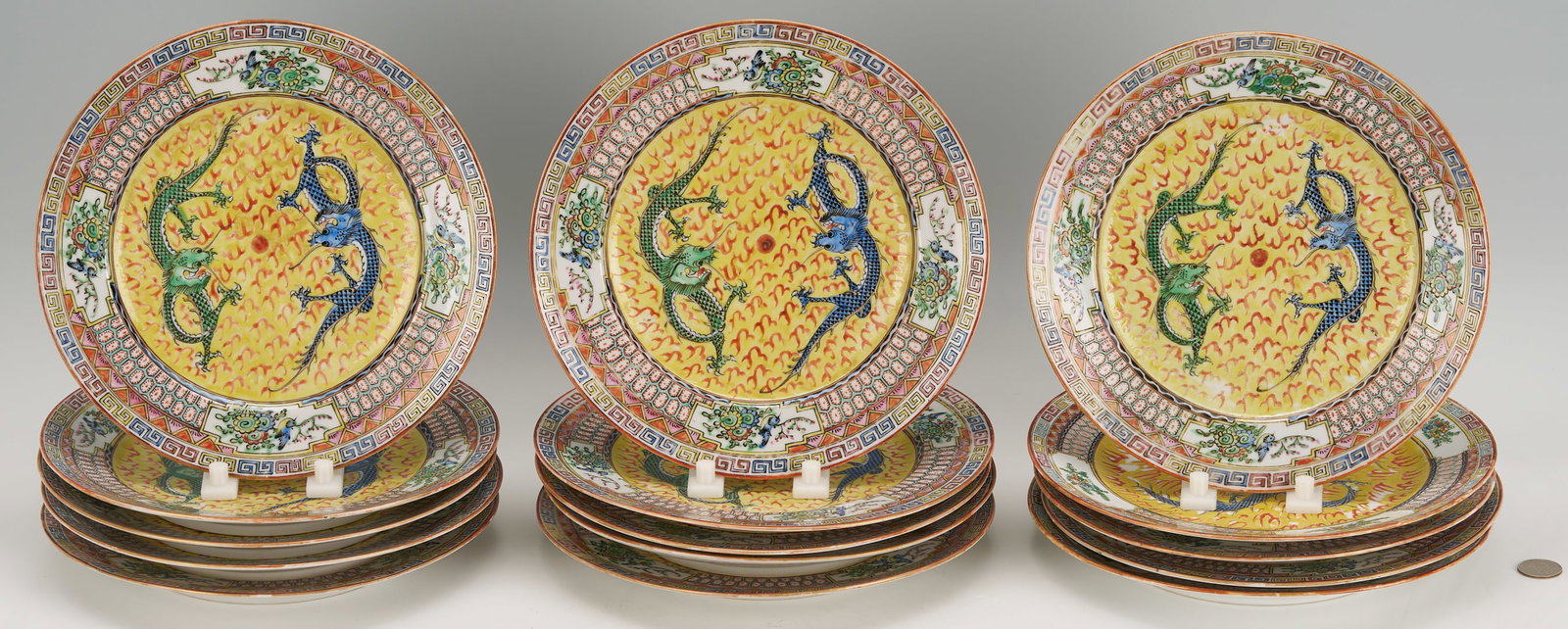 Set of 15 Chinese Porcelain Dragon Plates: Set of 15 Chinese porcelain plates, each decorated with two blue and green qilong dragons chasing a flaming pearl on a yellow ground. Triple borders with diaper and fret designs accented with floral s