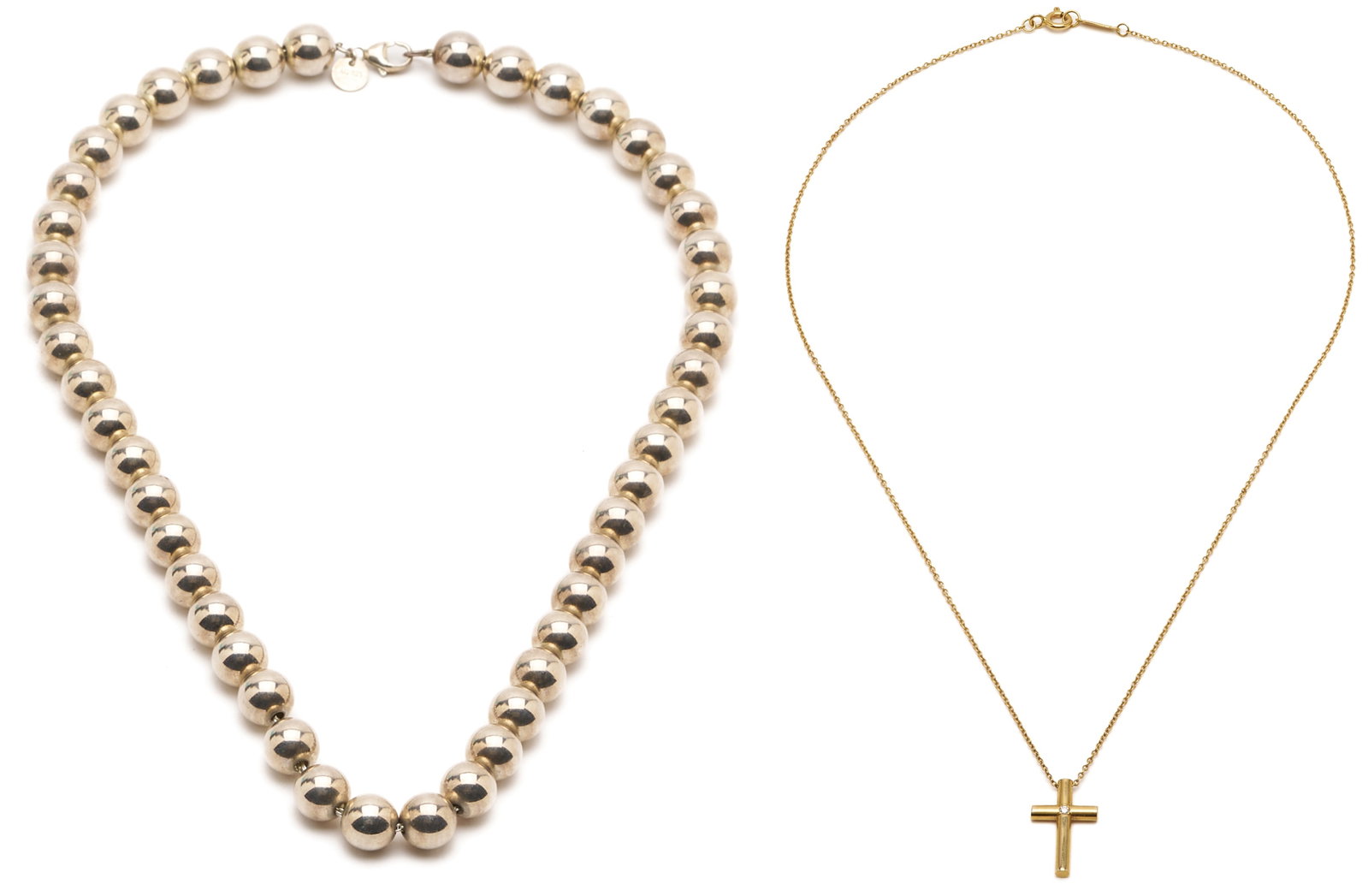 2 Tiffany & Company Necklaces, 18K Gold & Sterling Silver: 1st item: Ladies' 18K yellow gold cross pendant necklace by Tiffany and Company featuring an 18K cross inset with one diamond. Marked "Tiffany & Co." and "750" near the