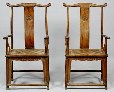 Pair of Chinese Hardwood Yokeback Armchairs, Modern: Pair of Chinese hardwood yokeback armchairs with carved dragon backs, carved skirts and woven cane seats, open mortise and tendon joinery. 47" H x 26 1/4" W x 19" D. 20th century/Modern.