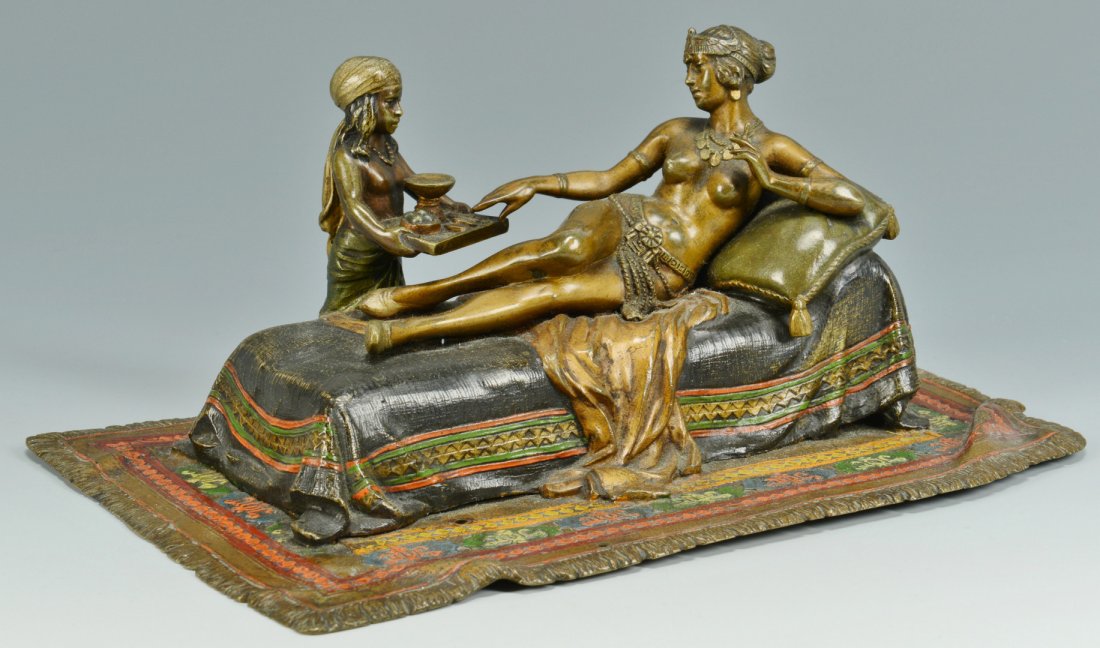 Cold Painted Bronze Cleopatra: Cold painted bronze, depicting a partially nude reclining female, possibly Cleopatra, on a chaise lounge with a child servant waiting on her, holding a tray. Attributed to Franz Xavier Bergmann (1861-