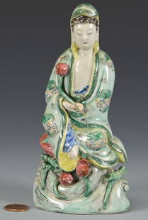 Famille Verte Guan Yin Figure: Chinese Famille Verte or Famille Rose ceramic figure of Guan-Yin, seated and attired in flowing green robes, holding a lotus bud. The presence of other lotus buds around her skirts suggests this may