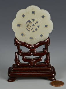 Carved White Jade Disc and Stand: Chinese white jade disc or pendant with scalloped and pierced outer edge, the interior carved as a Chinese letter or symbol. 2-1/4" diameter. Probably late 19th century. Includes carved hardwood