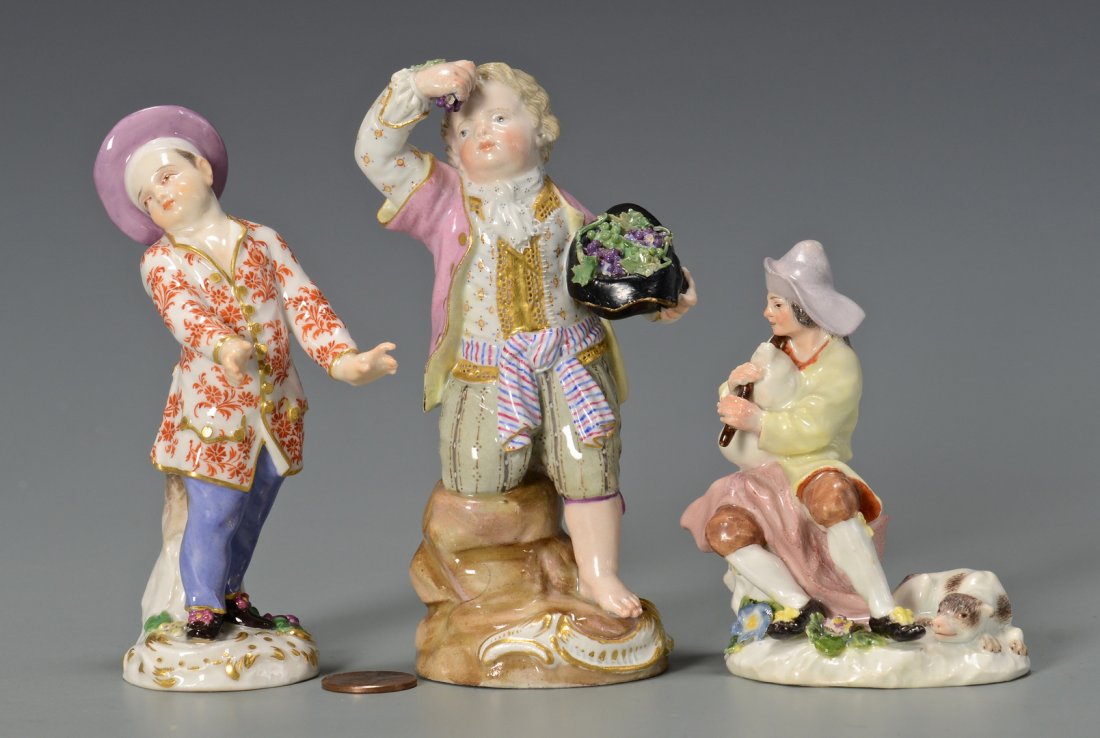 Three Meissen Figurines: Three Meissen porcelain figurines. 1st item: figure of a boy carrying a hat full of grapes, partially kneeling on a tree stump. Blue underglaze crossed swords mark with impressed signature F-- and imp
