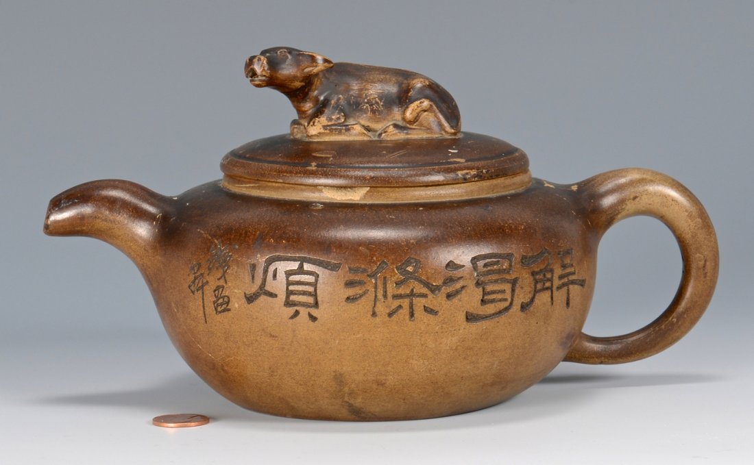 19th c. Chinese Yixing Teapot: 19th century Chinese Yixing pottery teapot having cow finial to top, makers seal mark to the underside of lid and maker's signature and inscription to the body. 5" H x 9 1/4" W.