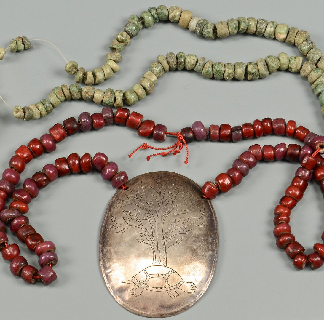 Trade Beads and Silver Gorget: 2 Fur Trade collectible items. 1st item: Silver trading gorget engraved with turtle and tree of life pattern, unsigned, with strand of red white-heart beads. 3-1/2" x 2-5/8" gorget, 24" L beads. Possi