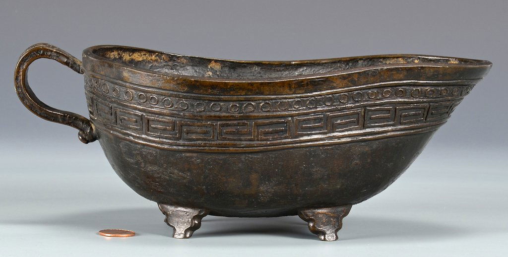 Chinese Bronze Wine Vessel: Chinese bronze wine vessel of oblong, pear shaped form, the body and handle decorated with a band of fret decoration, raised on four feet. Small lotus in oval mark to underside. 3 1/2" H x 10" L x 5 1