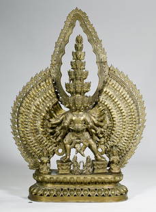 Bronze 43" Tibetan Avalokitesvara Sculpture: Large sectional gilt bronze Tibetan "Thousand Arm" Avalokiteshvara Buddha, holding various attributes and wearing a multi-headed crown against a mandorla, seated upon a double lotus base adorned with