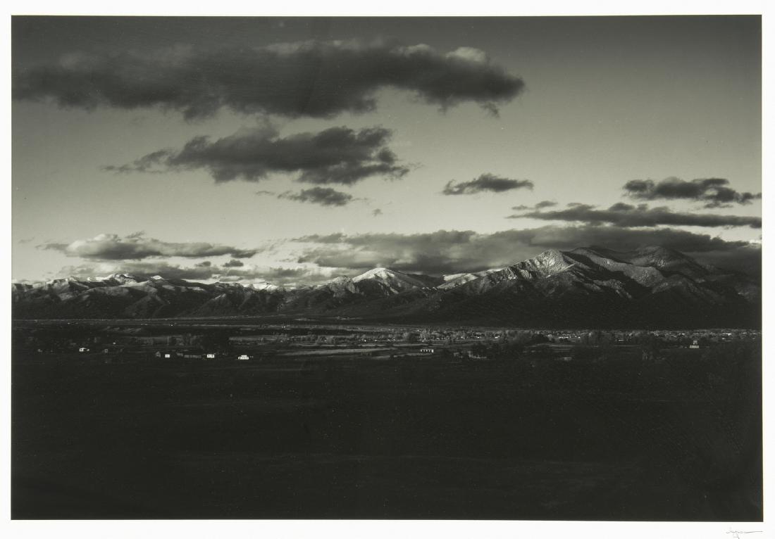 Jack Spencer Southwestern Photograph: Jack Spencer (b. 1951) gelatin silver print depicting a residential area in the Southwest, middle ground, against the Rocky Mountains, background. Signed "Spencer" on matte, lower right under image. H