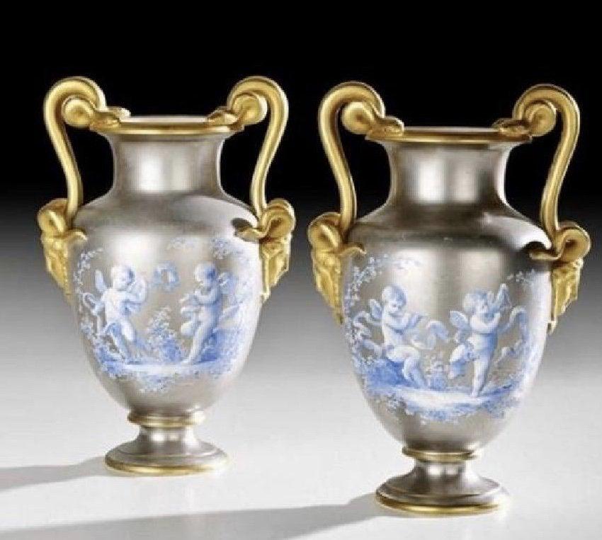 A PAIR OF 19TH C. PLATINUM GROUND PORCELAIN VASES: Pair of French Hand-Painted Platinum-Ground Porcelain Urns, fourth quarter 19th century, in the Neo-Grec taste, decorated with blue-painted trophies and allegories of music, with gilt snake-form handl