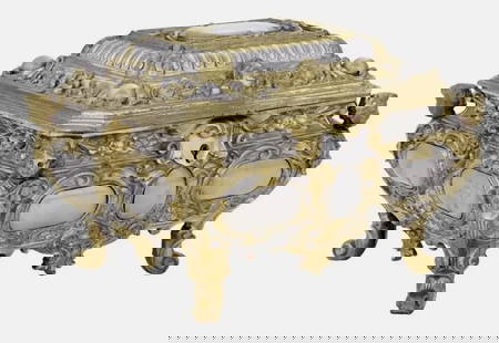 19TH C. FRENCH GILT AND SILVERED BRONZE JEWLRY BOX TIFFANY STUDIOS: fourth quarter 19th century, in the Baroque taste, the hinged cover with a central cabochon framed with scrollwork and winged angel heads, the body on scrolled feet supporting molded busts at each cor