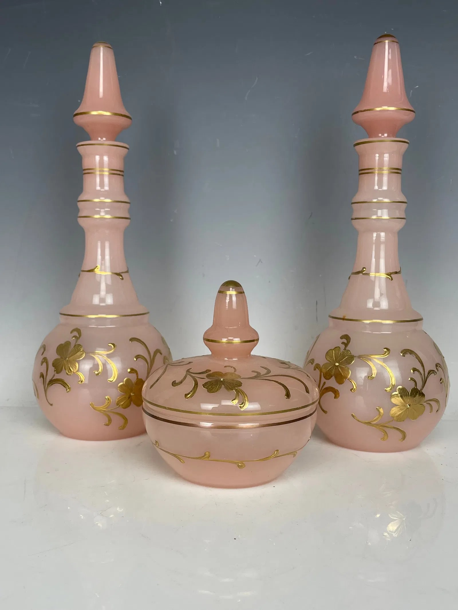 A PAIR OF ENAMELLED OPALINE PERFUME BOTTLES AND A LIDED DISH: Circa 1920. Bottles measure 9.5 inches tall. All in good condition. Estimate $300-500