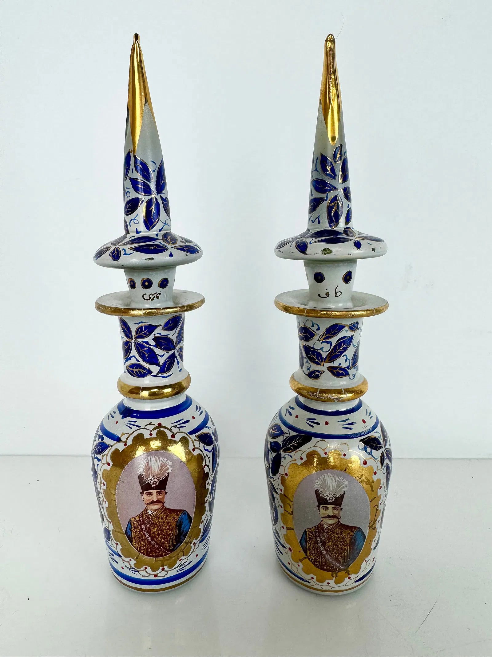 A PAIR OF PERSIAN MARKET OPALINE BOTTLES AND TOPS: Circa 1900. Both painted with Naseredin Shah of Iran portraits. Measure 7 inches h. In overall good condition. Estimate $800-1000