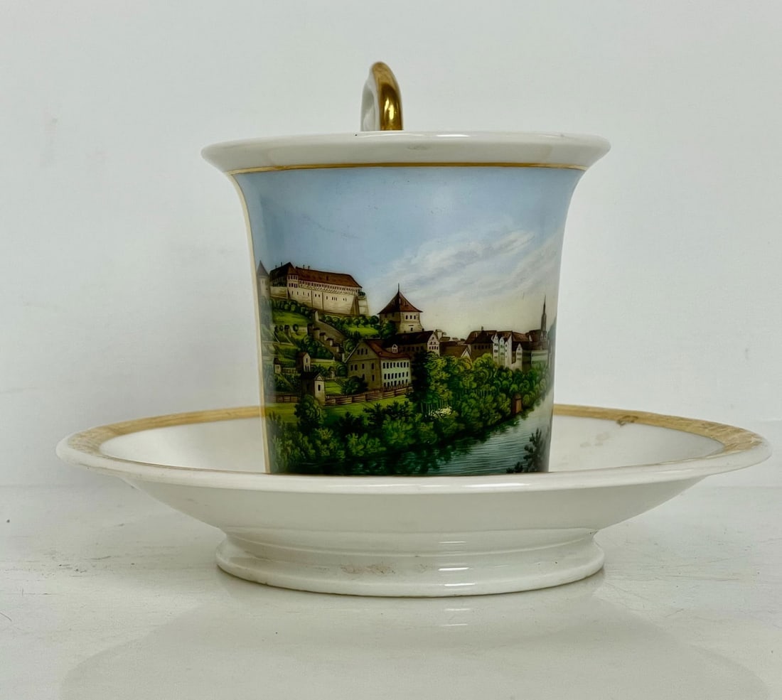 A CONTINENTAL TOPOGRAPHICAL PORCELAIN CUP AND SAUCER: Circa 1880. In good condition, no breaks, no damage. Estimate $500-600