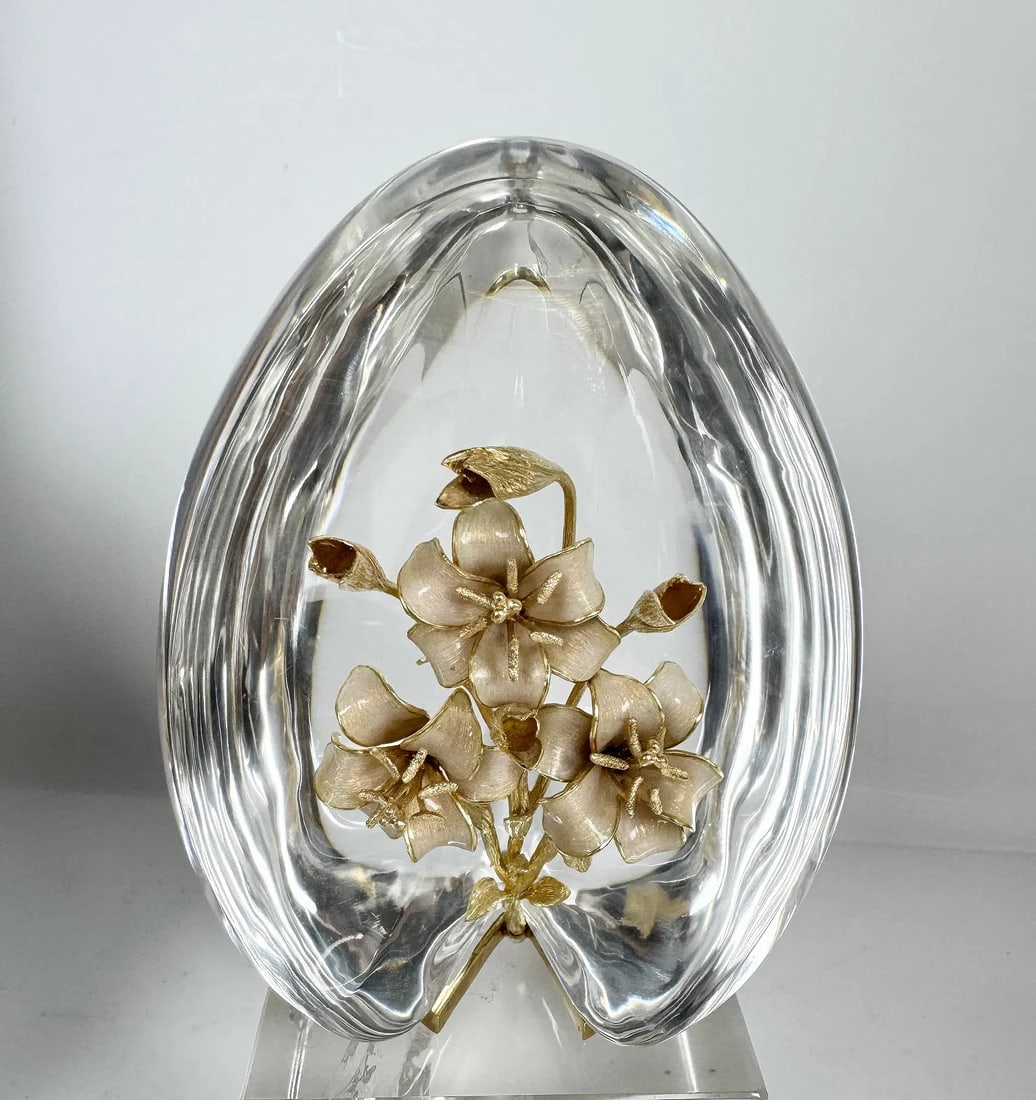 STEUBEN 18KT GOLD AND ENAMEL CRYSTAL EGG: American, 20th century. A Steuben crystal sculpture in egg form, having 18K gold flowers running up center and resting on gold stand, marked Steuben on crystal and 18K on base; ht. 4.75, wd. 3.75, dp.
