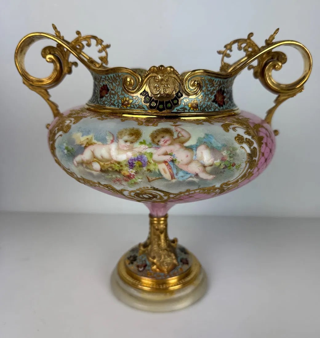 CHAMPLEVE ENAMEL AND SEVRES PORCELAIN VASE: Circa 1900. Measures 10 inches x 10 inches . In good condition. Minor loss of gilding. Estimate $1500-2000