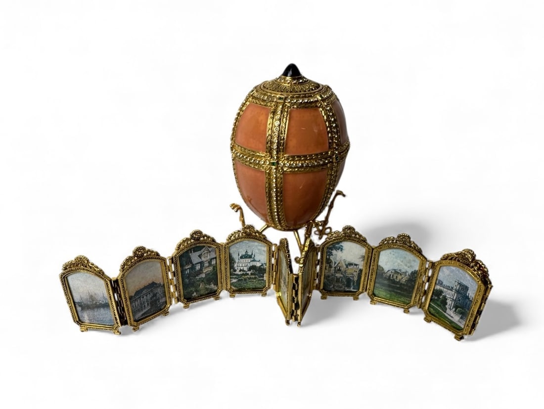 IMPERIAL FABERGE ENAMEL DANISH PALACE EGG: A Faberge Danish palace egg. Pink egg studded with crystals that opens on a hinge. Inside is an accordion style picture frame that depicts Danish monuments and places. Comes with base. 4 1/4" x 2