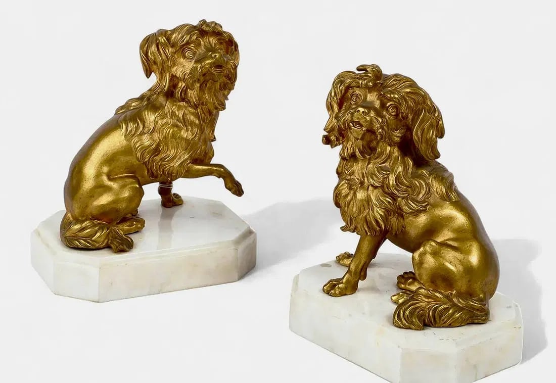 A PAIR OF DORE BRONZE OF SPANIELS: pair of French gilt bronze models of spanielsafter Jacques Caffieri (1678-1755)late 19th/20th centuryEach on a variegated white marble plinth.height 9 1/4in (23cm); width 8in (20cm); depth 5 3/4in (14