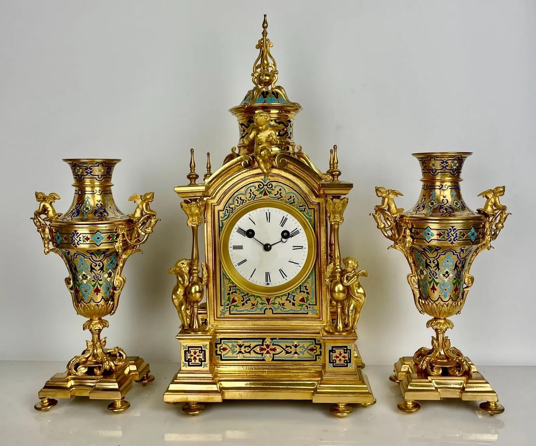 19TH C. FRENCH CHAMPLEVE ENAMEL CLOCK SET: Clock measures 24 inches high. Estimate $5000-6000