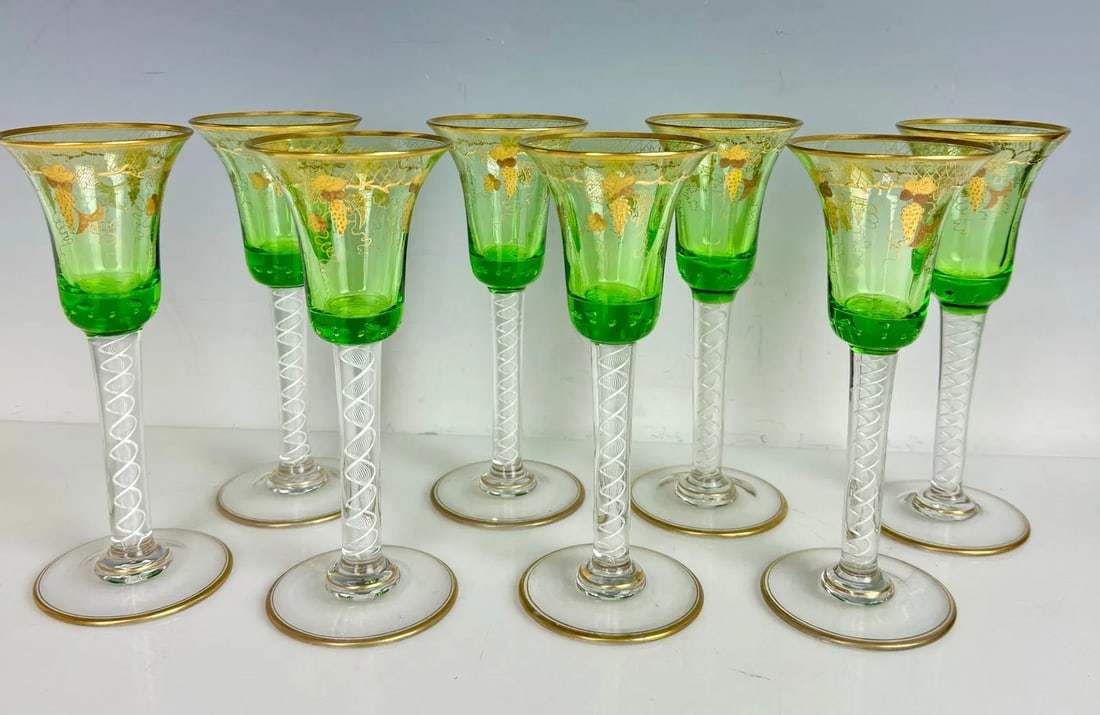 SET OF 8 ENAMELLED AND GILT LUDWIG MOSER GLASSES: Circa 1900. Each tall stem has a green bowl encircled with gilt relief grapes near the flared rim, and an interior ring of controlled bubbles in the green base just above the internally decorated