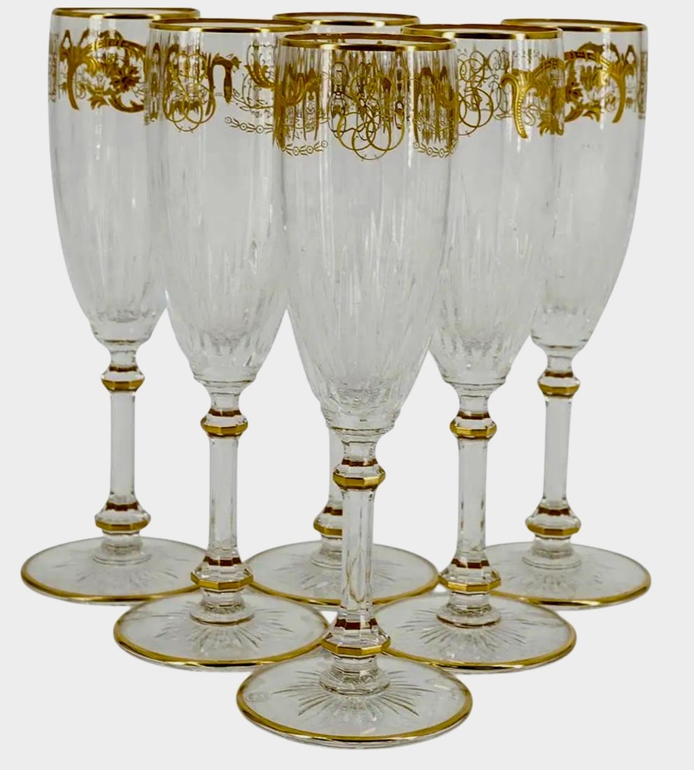 6 BACCARAT CHAMPAGNE FLUTES: Six Baccarat crystal champagne flutes, each featuring a ribbed body decorated with the "Imperator" pattern of gilt floral and foliage designs. Each piece is finished with gilt accents on rim and foot.