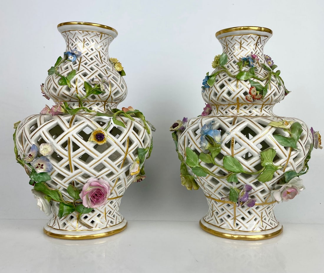APAIR OF RETICULATED FLOWER ENCRUSTED MEISSEN VASES: Circa 1900. Measure 10 inches tall. No breaks or cracks to the bodies. Chips and losses to encrusted flowers and petals. Estimate $1500-2000