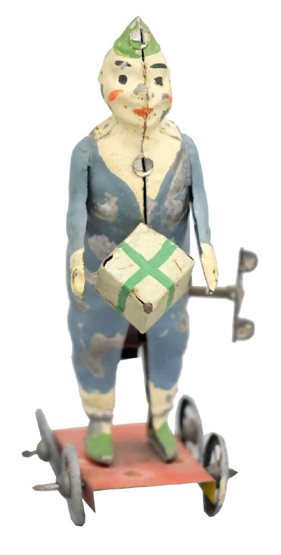 Clown with Present: Germany - Circa 1910 - 5" T The package twirls in his hand as he propels forward. The toy works well. Material: Tin