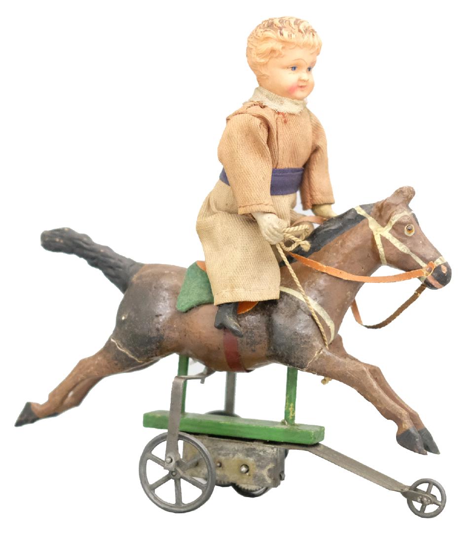 Boy Riding Horse: German - Circa 1915 - 6.75" L The boy goes up and down simulating that he is posting. The toy works well. Material: Composition, fabric, wood, celluloid, and tin