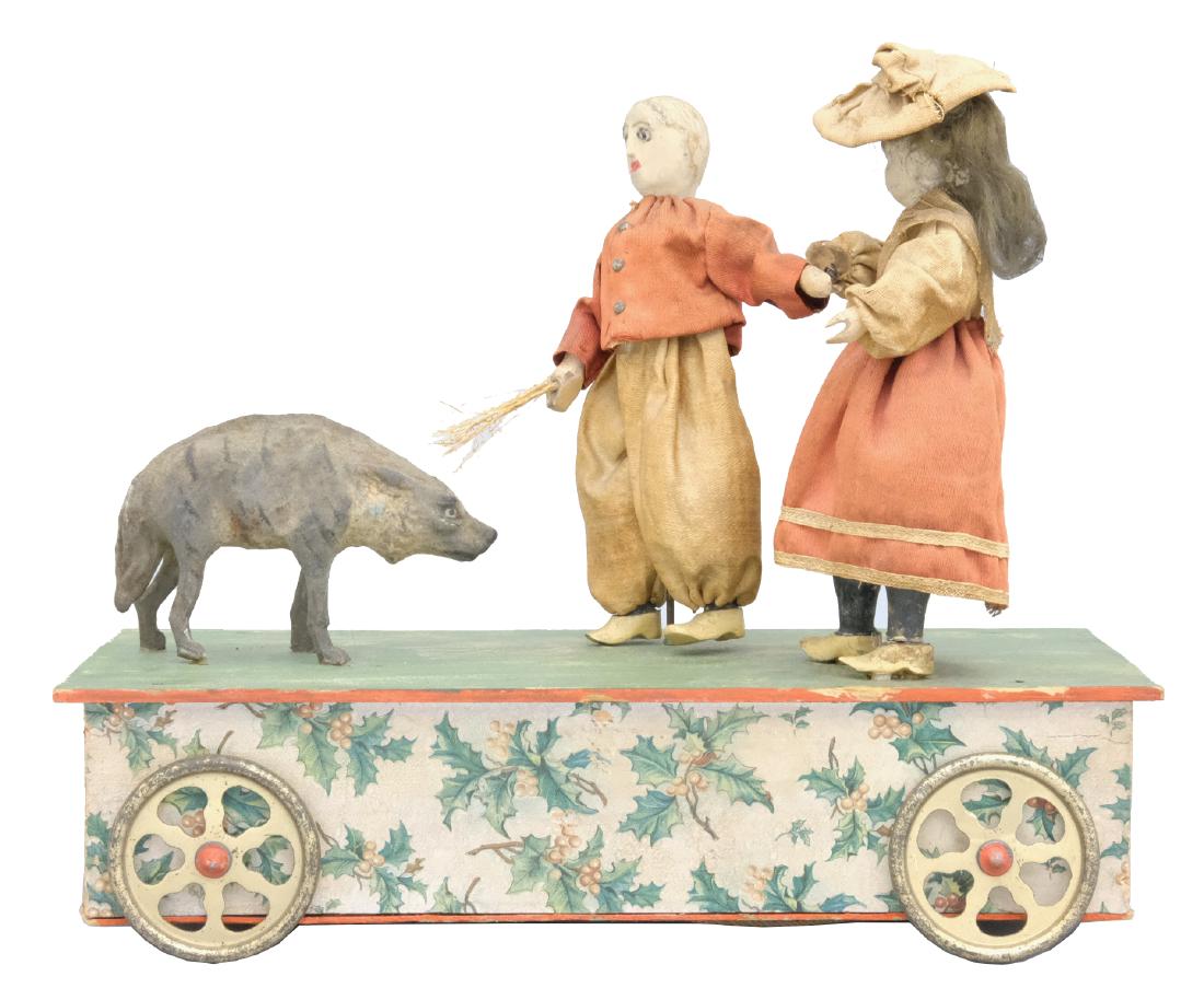 Boy Girl and Wolf Pull Toy: German - Circa 1910 - 10"L/8.5" T The boy and girl come upon a wolf during their walk. The boy turns to scare it away. The toy works well and music plays as it is pulled. Material: Composition, wood, 