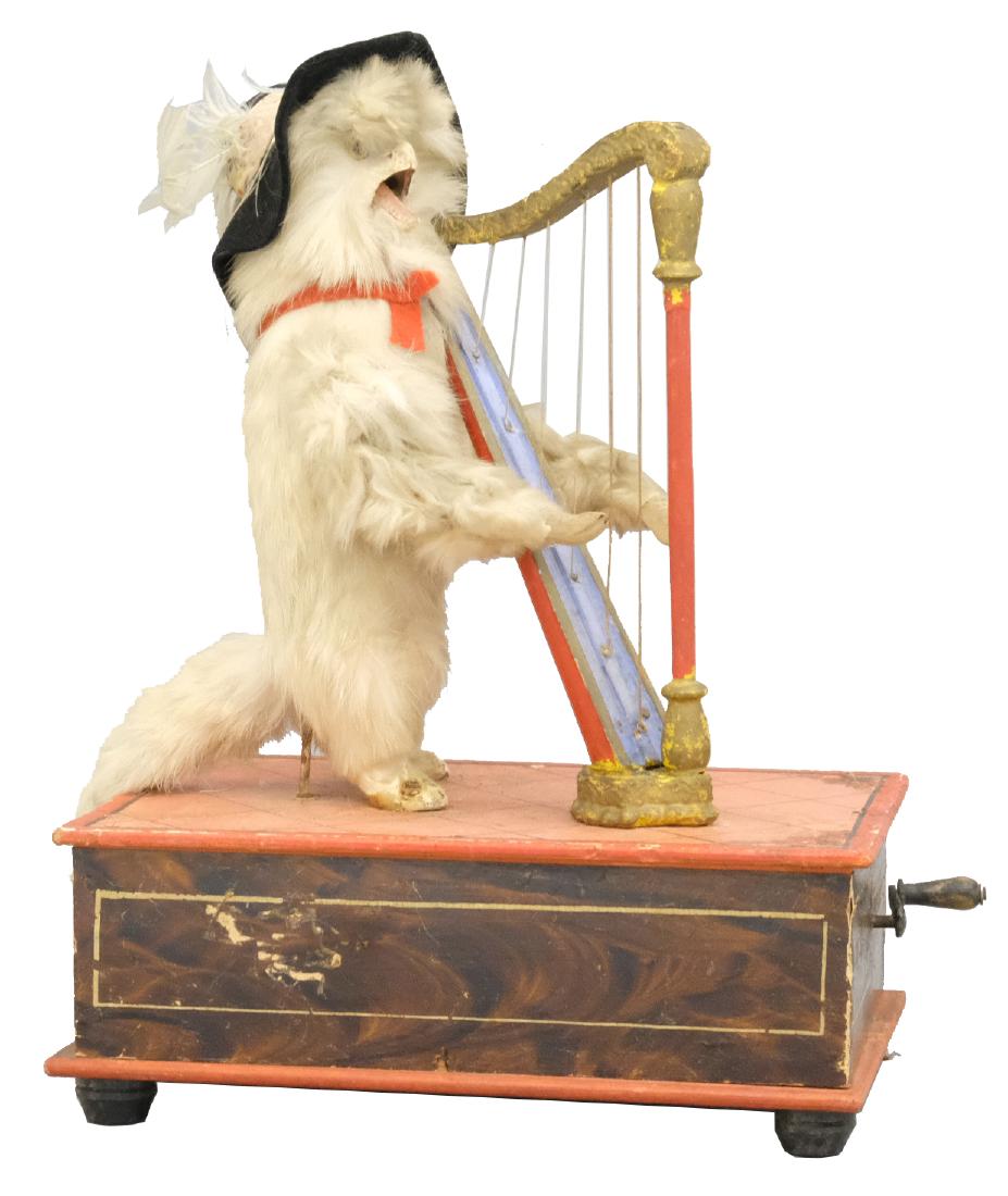 Puss N' Boots Playing the Harp Manneville: German - Circa 1915 - 11" T The crank mechanism works playing music but figure must be reconnected to show its movement. Material: Wood, fur, and fabric