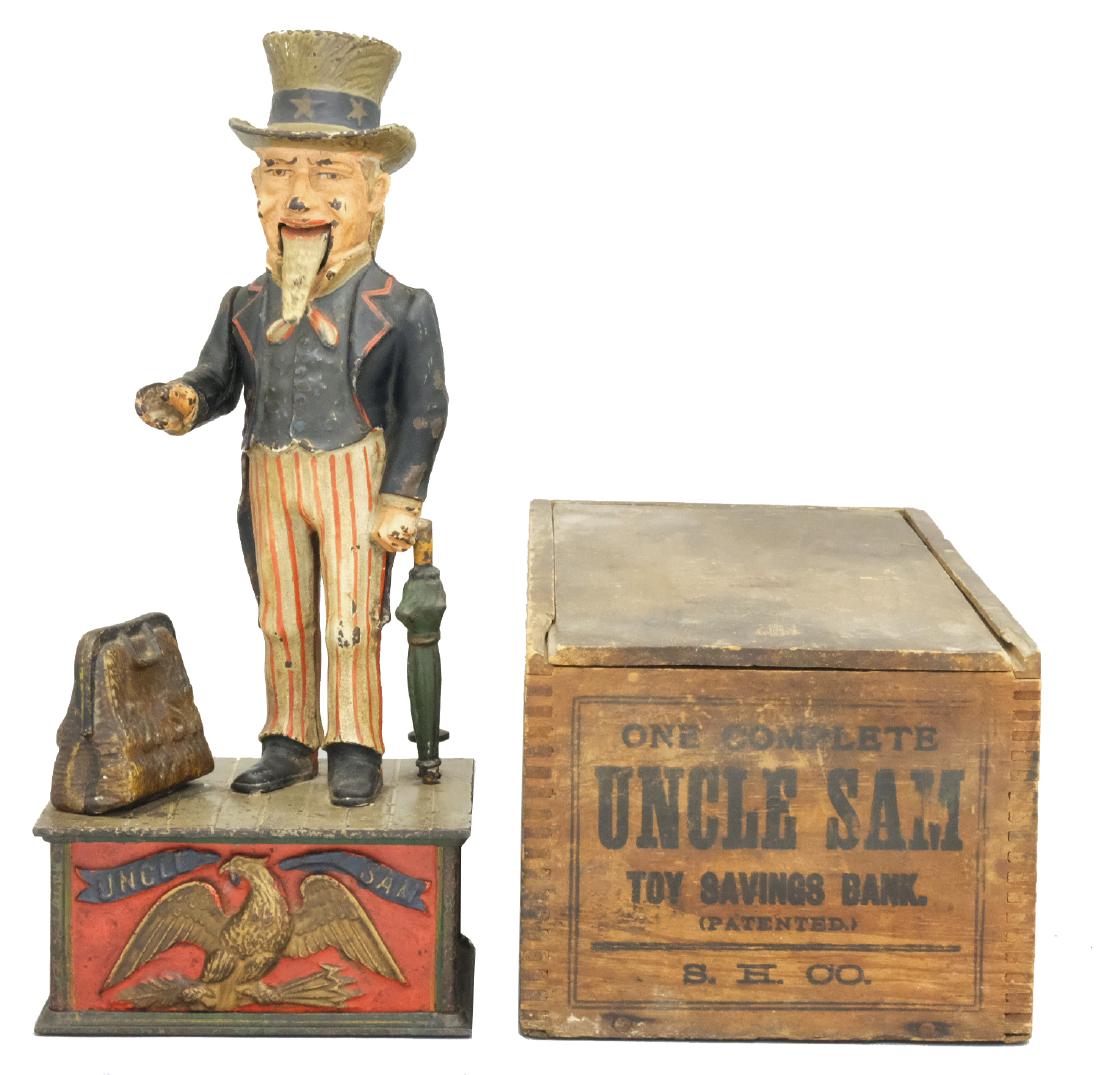 Uncle Sam Bank with Original Box: Shepard Hardware Co. Buffalo, NY - Circa 1896 Place a coin in Uncle Sam's hand, depress the lever and it drops into his satchel. Material: Cast Iron and Wooden Box. 3/4" crack in top plate.