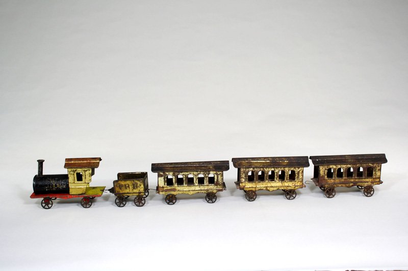 American Tin Floor Train “Skip” Cast Iron: Made by James Fallows Philadelphia, Pennsylvania – Circa 1895 This train includes the locomotive, tender and three passenger cars. When the toy is assembled it is 27” long. Material: Tin