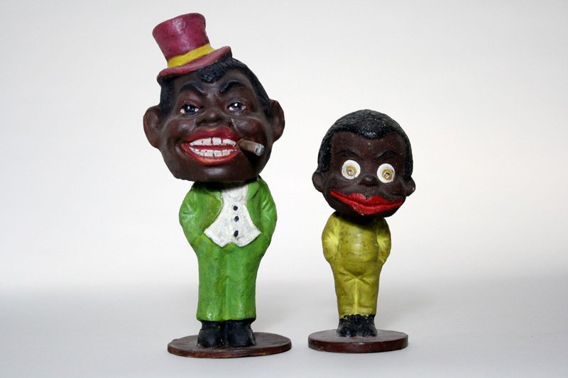Lot: Two Articulated Nodders: German – Circa 1910 Here are two wonderful nodders: a young black boy (5” tall), and a black man smoking (7 ½” tall). Material: Composition