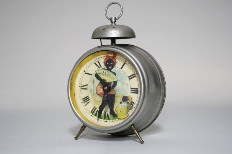 Black Mammy with Cradle Alarm Clock: German – Circa 1920 When wound the mammy rocks the cradle from sideto-side. This clock is bright, beautiful and still works very well. Material: Tin