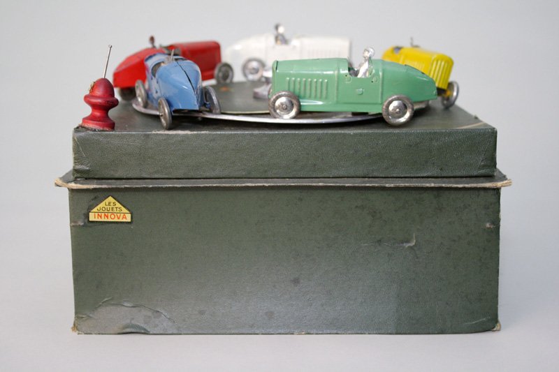 Racecar Jeu-de-course in Box Wind Up Toy: Made by Innova French – Circa 1935 This is a parlor gambling device depicting five colorful racecars going around in a circle. One spins the dial, the car stopping close to the red marker is the win