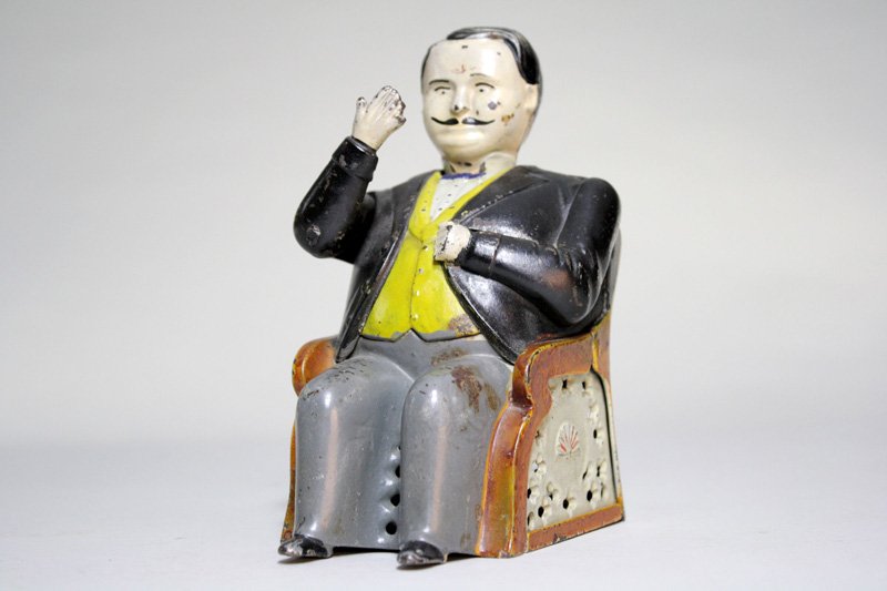 Tammany Bank – Little Fat Man Mechanical Bank: Made by the J. & E. Stevens Company Cromwell, Connecticut – Circa 1880’s Place a coin in his hand and its weight causes the hand to lower and deposit the coin into his pocket. His nod signifies th