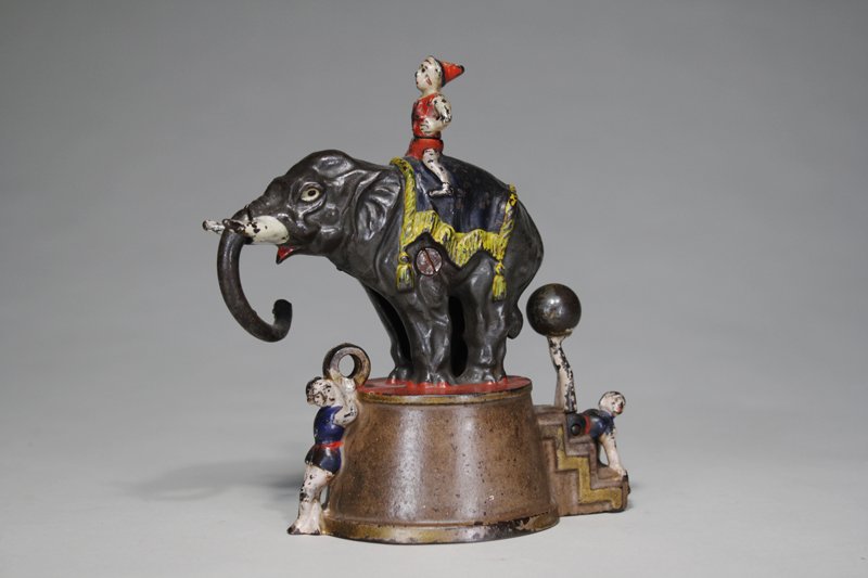 Elephant and Three Clowns Mechanical Bank: Made by the J. & E. Stevens Company Cromwell, Connecticut – Circa 1882 Place a coin in the gold rings held by the clown beneath the elephants trunk. Pull the legs of the clown spinning the ball and 