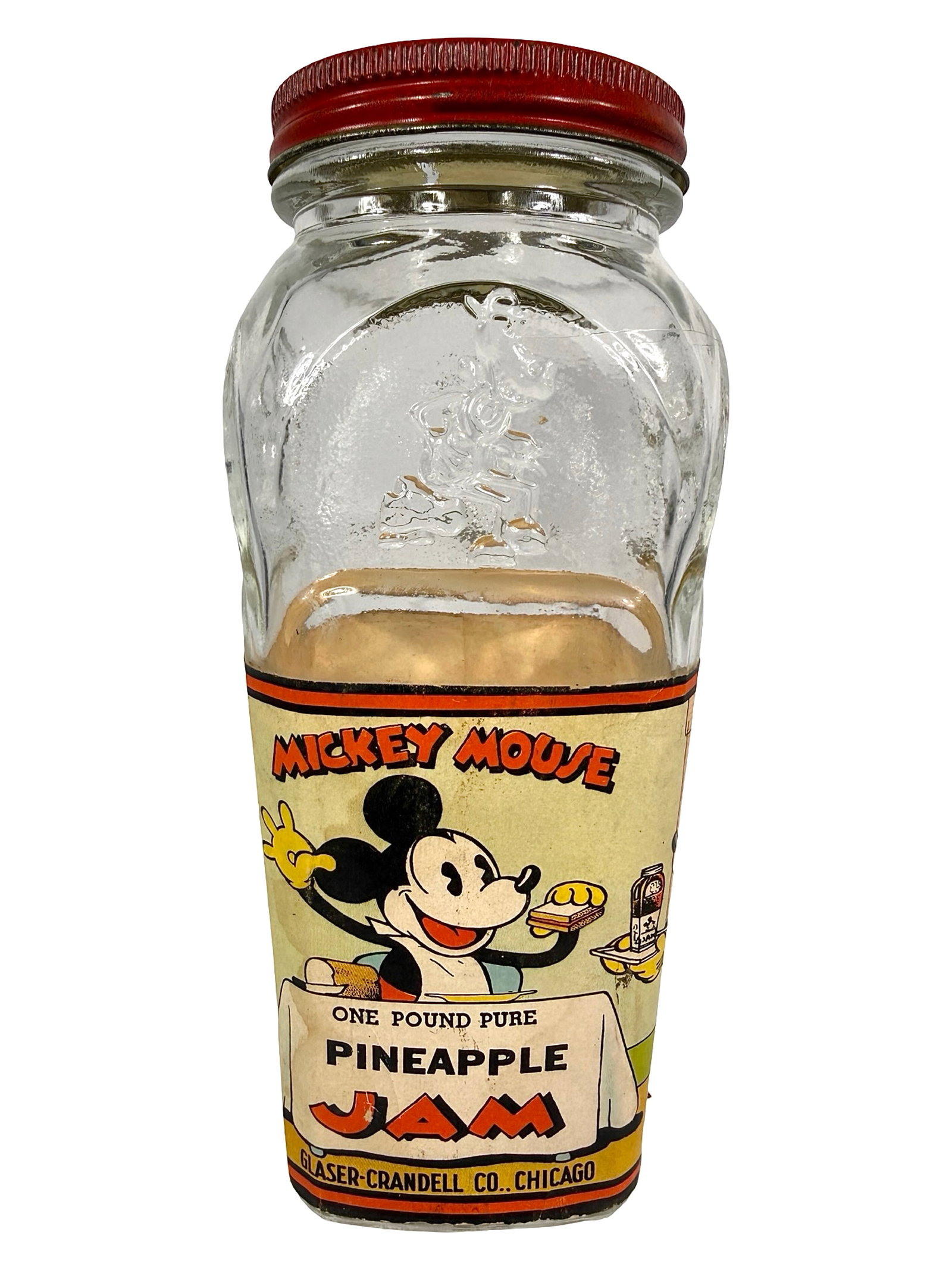 Mickey Mouse Pineapple Jam Glass & Paper Bank: Made by Glaser - Crandell Co. Chicago, IL - 1930's. 6" Tall x 2 3/4" Wide x 2 3/4" Deep. Bob and Shirley Peirce Collection.