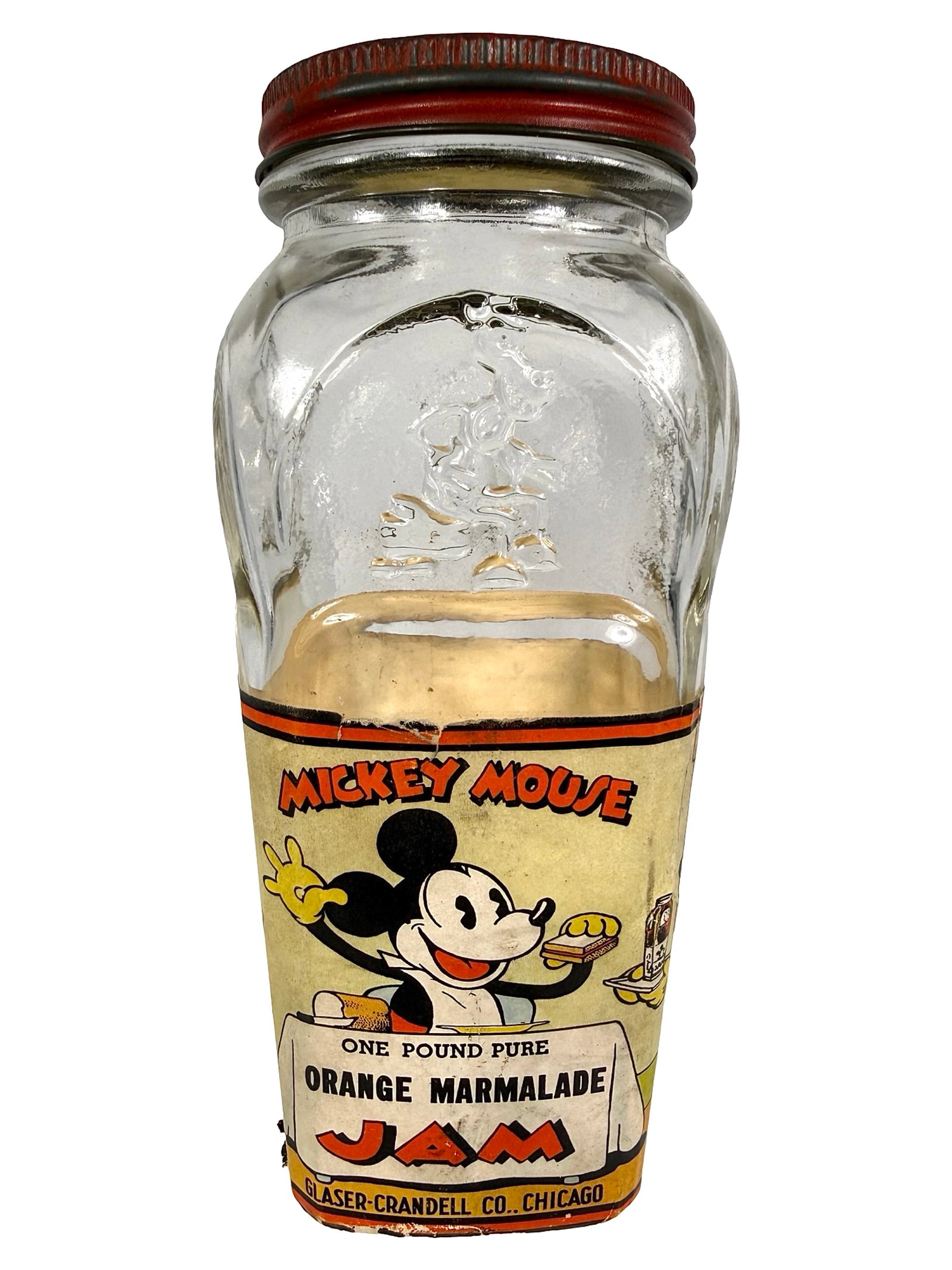 Mickey Mouse Orange Marmalade Jam Glass & Paper Bank: Made by Glaser - Crandell Co. Chicago, IL - 1930's. 6" Tall x 2 3/4" Wide x 2 3/4" Deep. Bob and Shirley Peirce Collection.