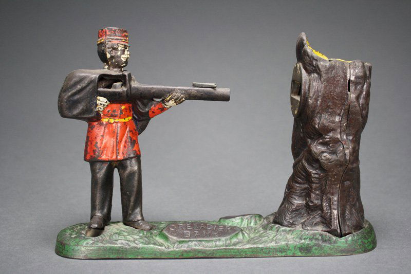 Grenadier Bank Mechanical Bank: John Harper & Co. England - Circa 1890 This is a classic and scarce English coin shooting bank. Material: Cast Iron