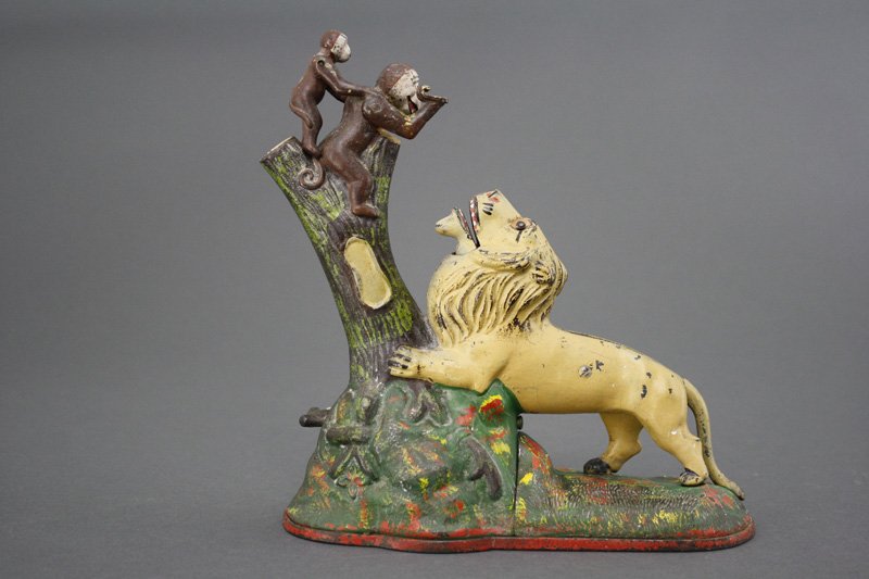 Lion and Monkeys (Double Peanut) Mechanical Bank: Manufactured by the Kyser & Rex Company Philadelphia, Pennsylvania - Circa 1883 To operate the bank, place a coin in the monkey's palm and press the lever. The monkey deposits the coin into the lion's