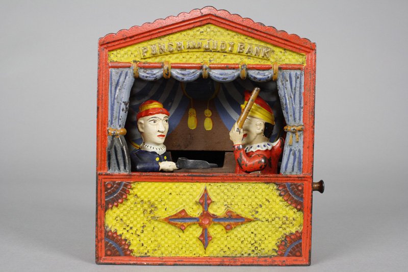 Punch and Judy, Small Letters Mechanical Bank: Shepard Hardware Company Buffalo, New York - Circa 1884 Pull out the top lever to lock the figures in place. Put a coin on Judy’s dust tray and press the lower lever. Punch will rush forward to admo