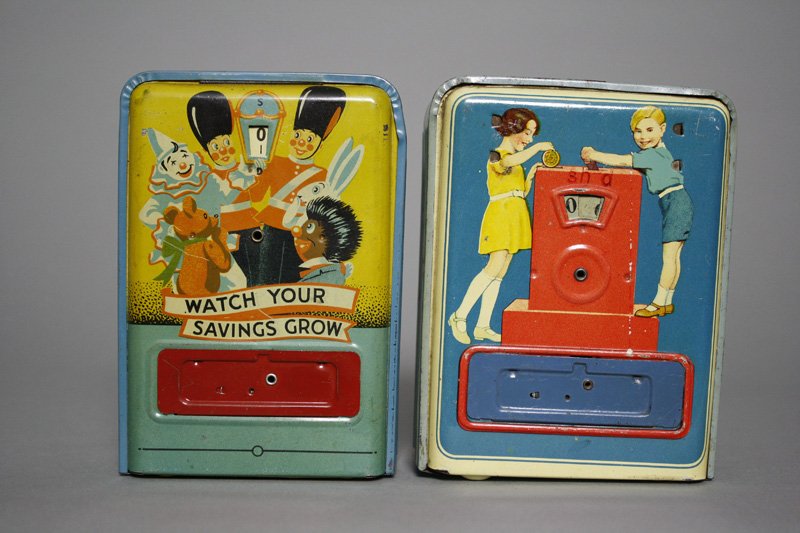 Watch Your Savings Grow” and Two Children Playing: English / German - Circa 1935 Two attractive, colorful banks; each about 5.25” tall. Material: Tin