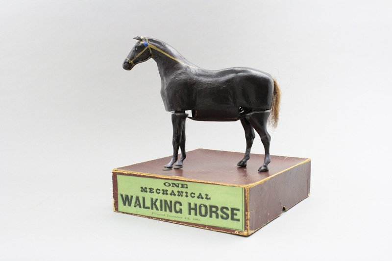 Mechanical Walking Horse: Probably Ives, Blakeslee Company Connecticut - Circa 1883 - 8.5” Long To our knowledge this is the only known boxed specimen of this toy. It is papier mache and cardboard with cast iron legs. It wor