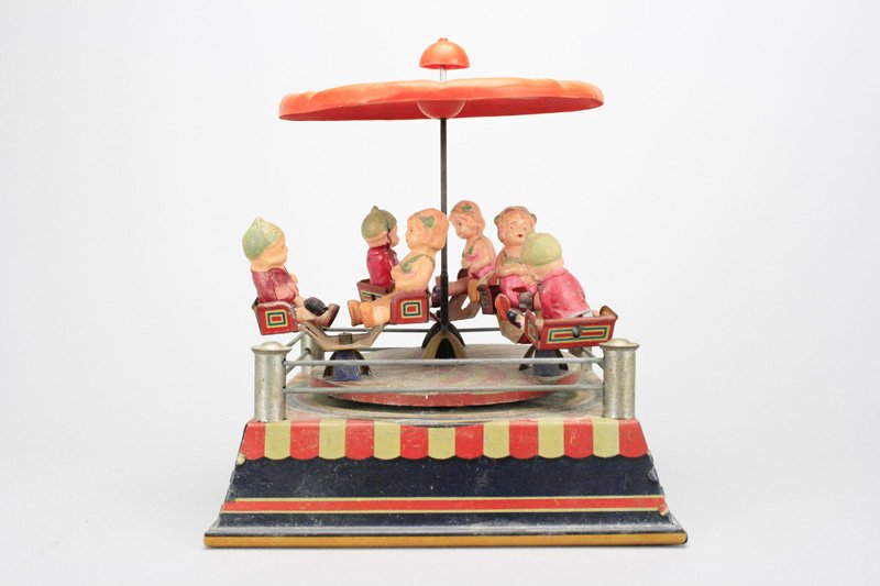 Whirling Go Round Japanese: Circa 1935 - 6.5” Square The canopy and platform spin around and the gondolas turn separately, as a bell is rung. It works well. Material: Tin and Celluloid