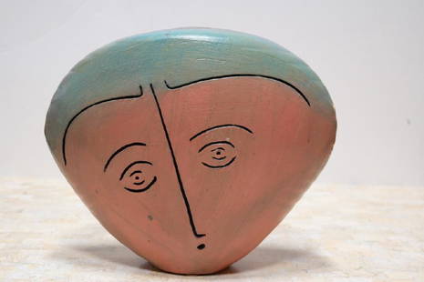 Ceramic Sculpture of a Head with Two Faces: Ceramic sculpture with face carved into either side in shades of coral and dusty pink with aquamarine and even lavender at the very top. Sculpture cannot be used as a vessel – though it does come