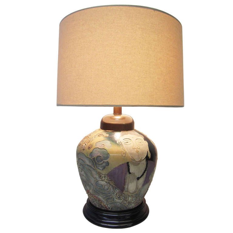 Asian-Influence Lamp by Frederick Cooper: The base of this large table lamp features intricate Asian artwork depicting two faces separated by waves. The embossed and glazed design is vibrant and detailed. The beige linen shade has a 17" diame