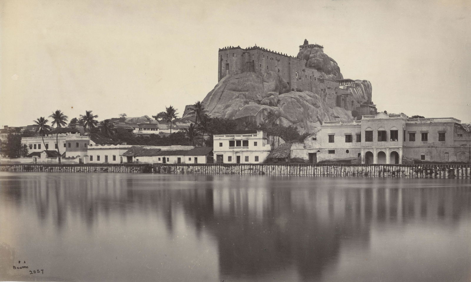 The Rock of Trichinopoly from the Tank on the West: The Rock of Trichinopoly from the Tank on the West. Samuel Bourne #2057. Photographer's credit and number in negative. Very good contrast and tonality.minor edge fading. 7.125 x 12.125 in.