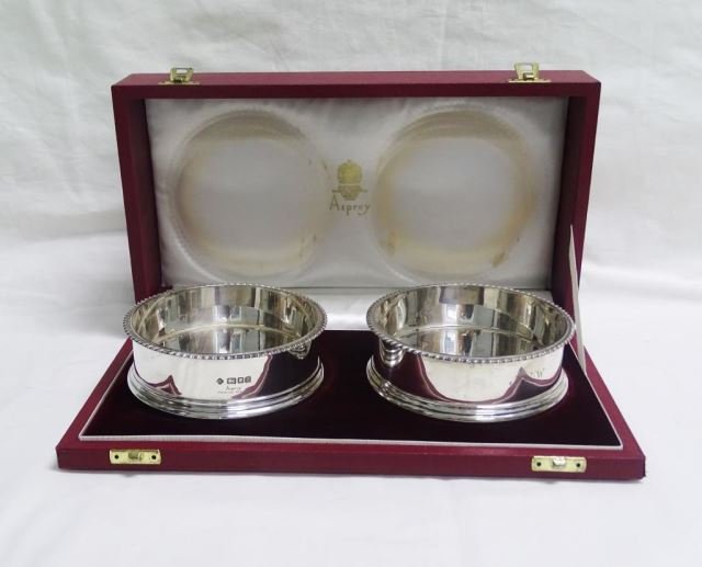Pair Asprey Sterling Wine Coasters in Box: Pair Asprey Sterling Wine Coasters in Box In the original red leather presentation box. The sterling coasters are hallmarked, with wood and felt lined bottoms. Diameter - 5 inches. Monogrammed "JWW" 2