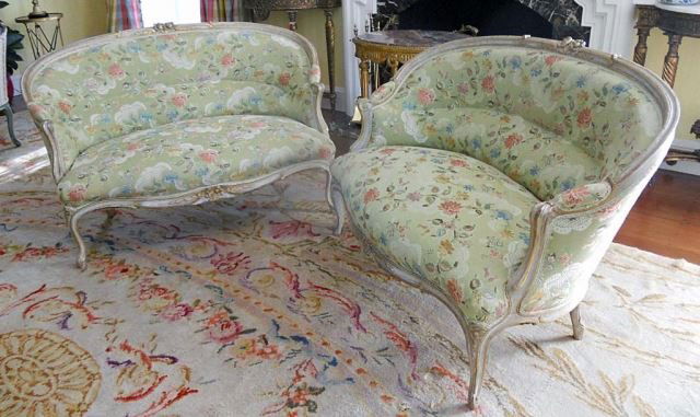 Pair Louis XV Style Carved & Upholstered Settees: 19th century the fabric is possibly Fortuny or of similar quality. The crest rails and skirt are carved with foliate motif, on cabriole form legs ending is scroll feet, tight upholstered back, arms, s